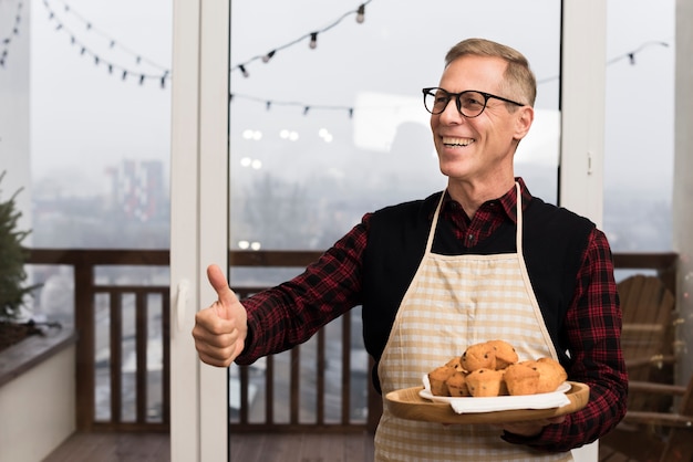 Padre felice che dà i pollici in su mentre si tiene la zolla di muffin