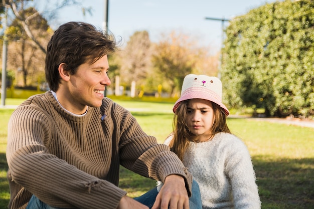 Free photo happy father sitting in front of his daughter in park