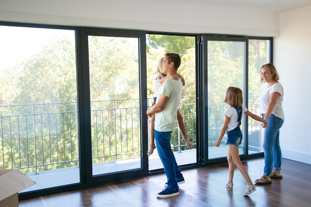 Happy father with daughter standing near open balcony and smiling