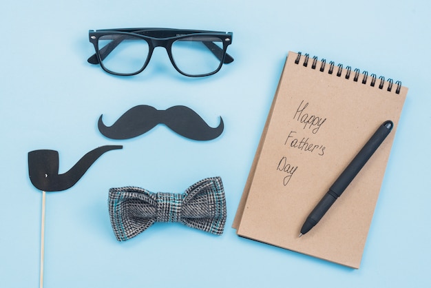 Foto gratuita iscrizione felice giorno di padri nel blocco note con occhiali e baffi