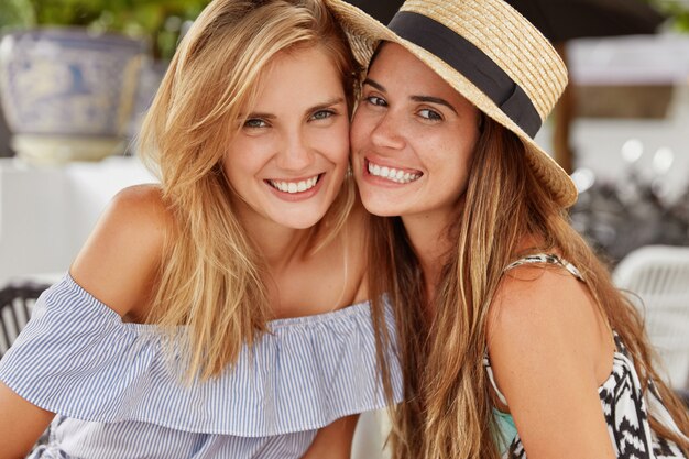 Happy female best friends sit at outdoor restaurant