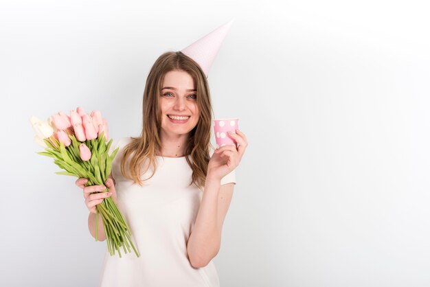 꽃을 가진 생일 모자에 행복 한 여성