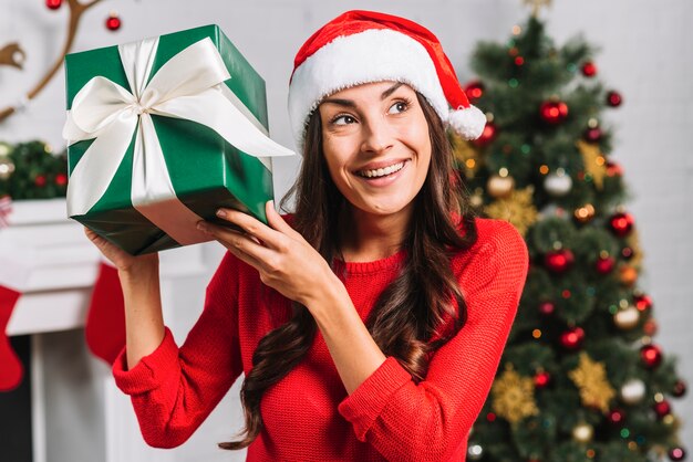 Happy female in Christmas hat holding present box