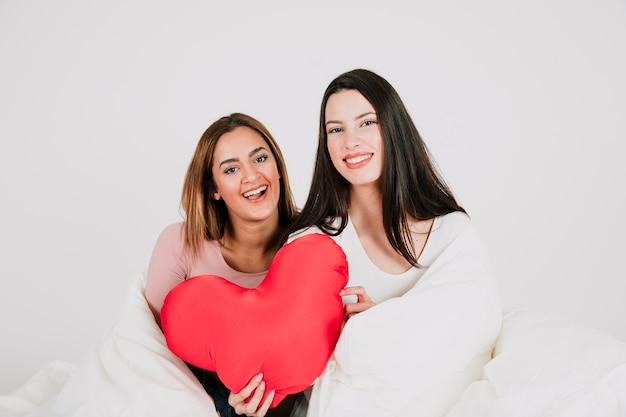 Happy female couple with heart in blanket