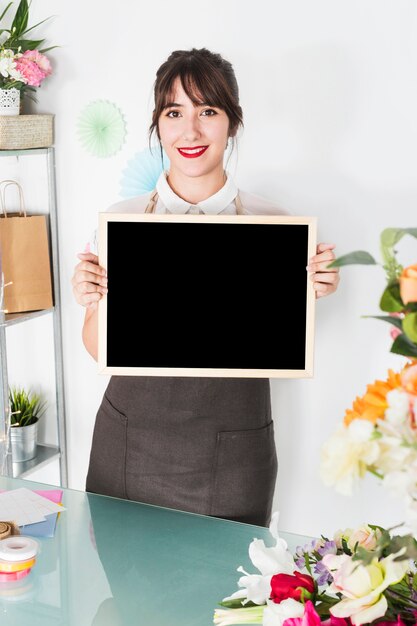 Happy female florist holding blank slate