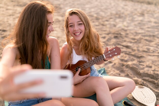 Счастливые женщины-друзья, наслаждаясь на пляже, принимая selfie