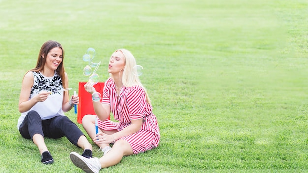 Счастливые женщины-друзья, наслаждаясь пузырями в парке