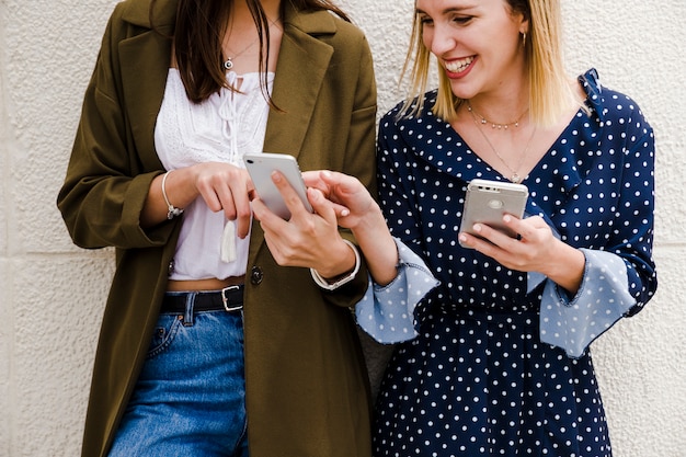 Free photo happy female friends pointing at something in mobile phone