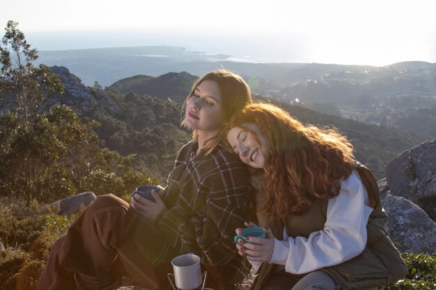 Happy female friends resting on top of mountain together