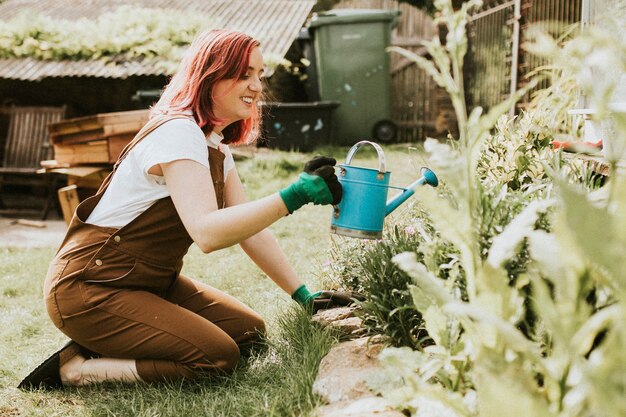 幸せな女性の庭師の水やり植物