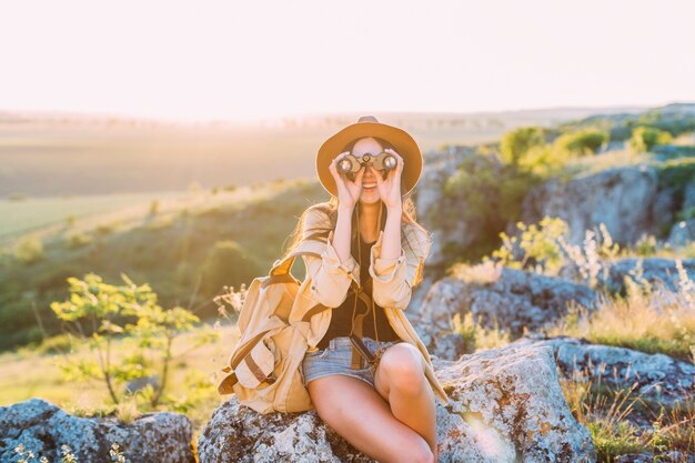 Happy female hiker looking through binocular