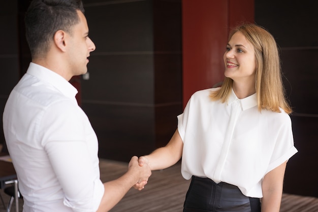 Free photo happy female manager greeting male partner with handshake.