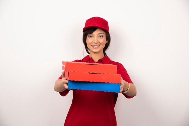 Happy female pizza delivery worker giving three cardboards of pizza.
