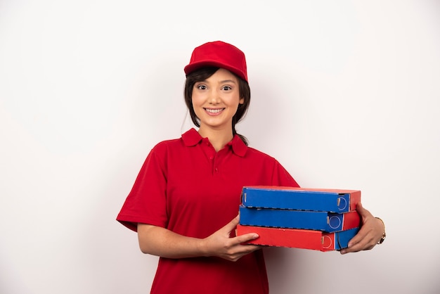 Happy female pizza delivery worker holding three cardboards of pizza.