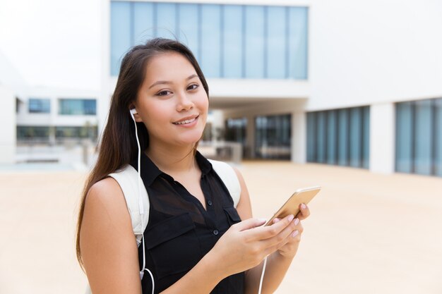 Happy female student listening to music on cell