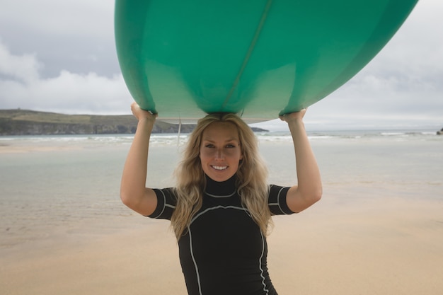 Happy female surfer carrying surfboard on head in beach