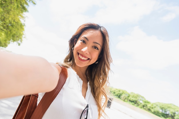 Foto gratuita felice turista femminile prendendo il suo autoritratto all'aperto