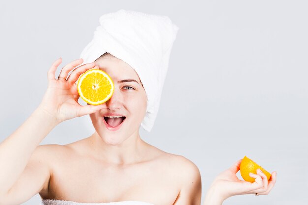 Happy female in towel with oranges at face