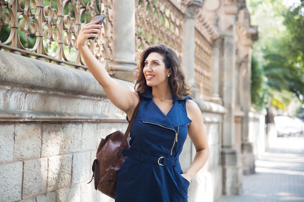 Happy female traveler taking selfie in street