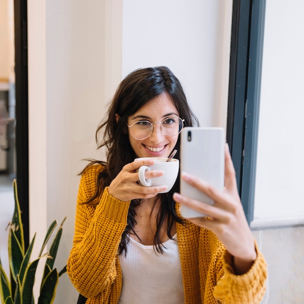Счастливый женщина с чашкой, получая selfie, улыбаясь