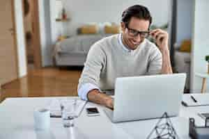 Free photo happy freelance worker using computer while working at home