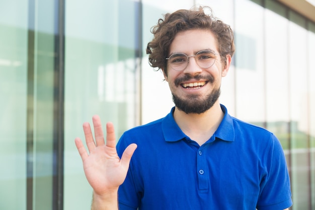 Happy friendly guy wearing glasses, waving hello