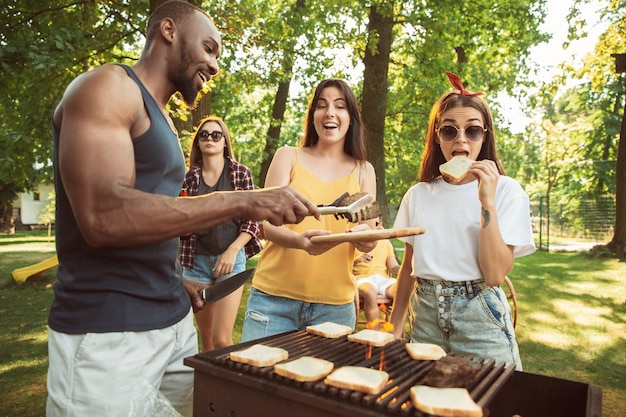 Happy friends are having beer and barbecue party at sunny day