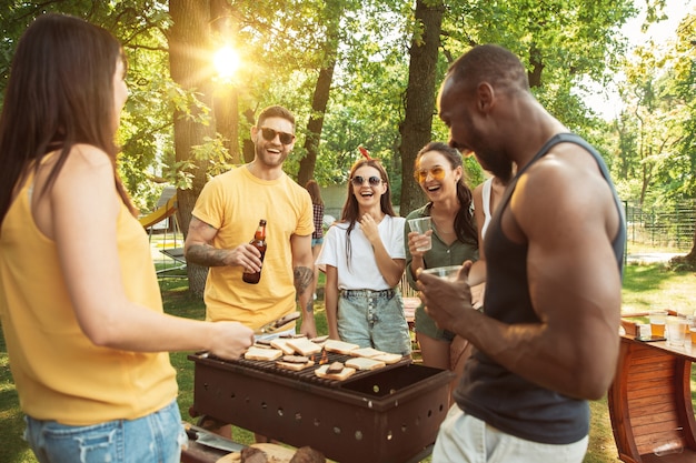 Happy friends are having beer and barbecue party at sunny day