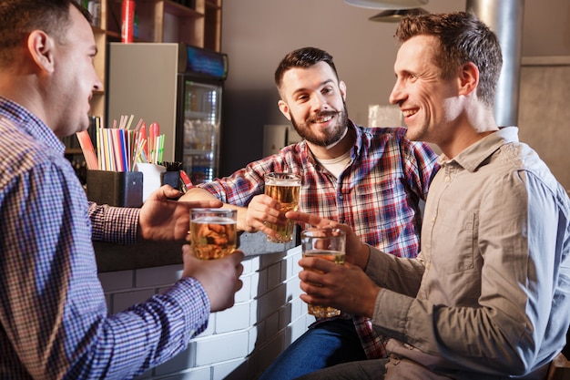 Happy friends drinking beer at counter in pub