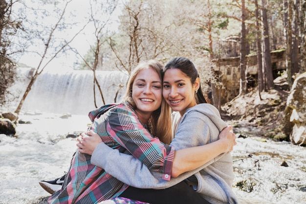 Happy friends embracing each other outdoors