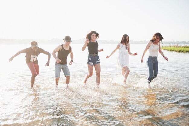 행복한 친구들은 해변에서 즐거운 시간을 보냅니다.-여름 방학에 야외 물에서 노는 젊은 사람들.