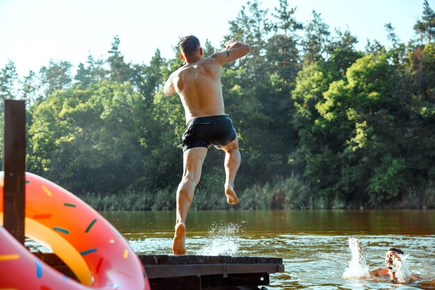 Happy friends having fun, jumping and swimming in river