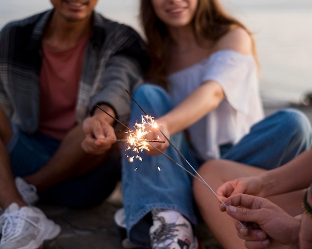 Happy friends holding fireworks close-up