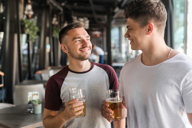 ビールの眼鏡を持っている幸せな友達