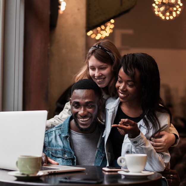 Happy friends looking at laptop indoors