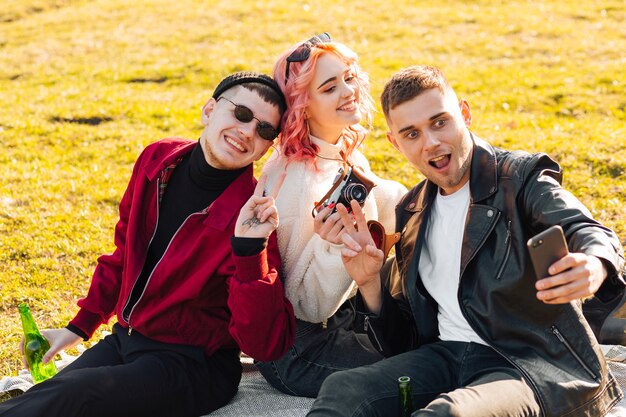 Happy friends taking selfie sitting on grass and having fun 