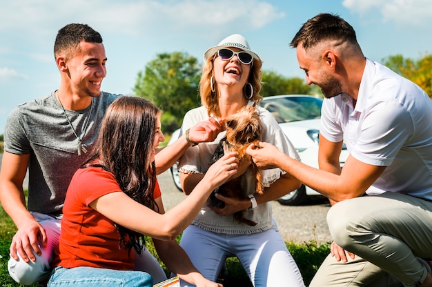 Foto gratuita amici felici con cane carino all'aperto