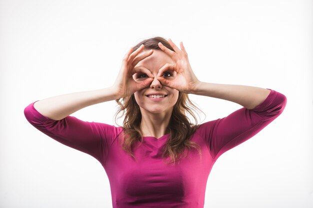 Foto gratuita donna divertente felice con le mani del binocolo che guarda l'obbiettivo