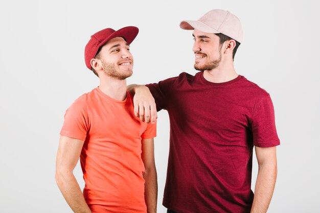 Happy gay couple in caps standing close