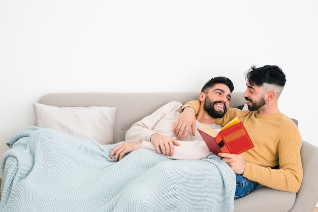 Happy gay couple lying on sofa looking at each other