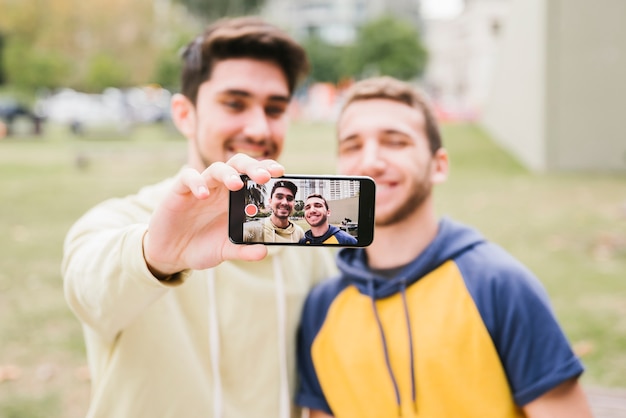 Happy gay couple shooting selfie on street