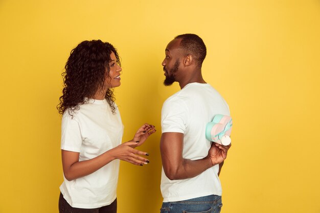 Happy to get gift. Valentine's day celebration, happy african-american couple isolated on yellow studio background. Concept of human emotions, facial expression, love, relations, romantic holidays.