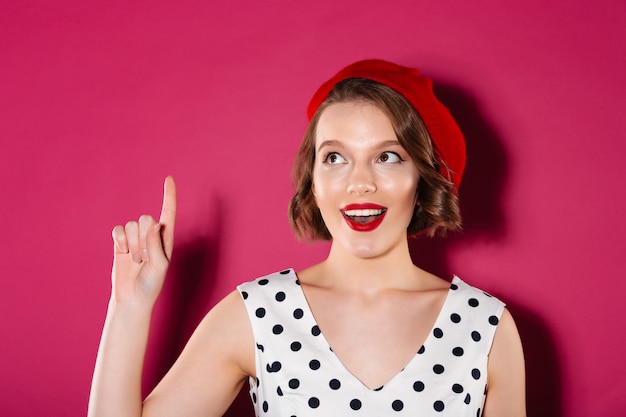 Donna felice dello zenzero in vestito che ha idea e che distoglie lo sguardo sopra il rosa