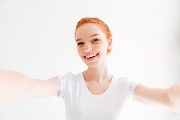 Selfieを作ると探しているtシャツで幸せな生姜女