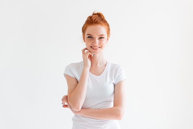 Happy ginger woman in t-shirt with hand near face looking