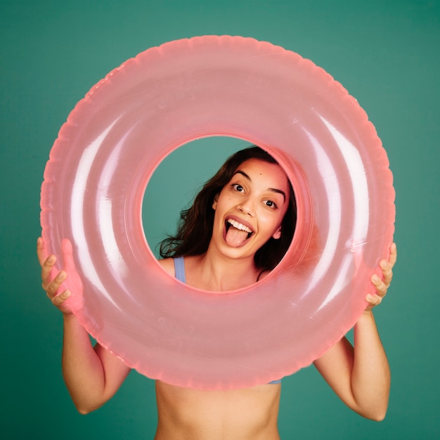 Happy girl in bikini looking through inflatable ring