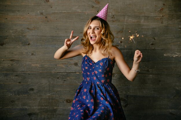 Happy girl celebrating birthday party, showing peace sign, holds the bengal light