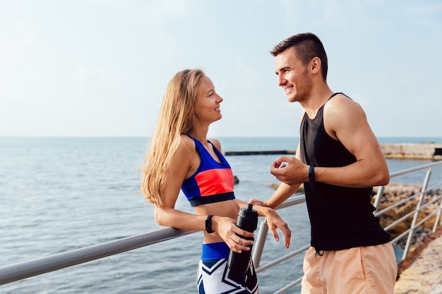 Happy girl in colorful sportswear having pleasant conversation with her boyfriend 