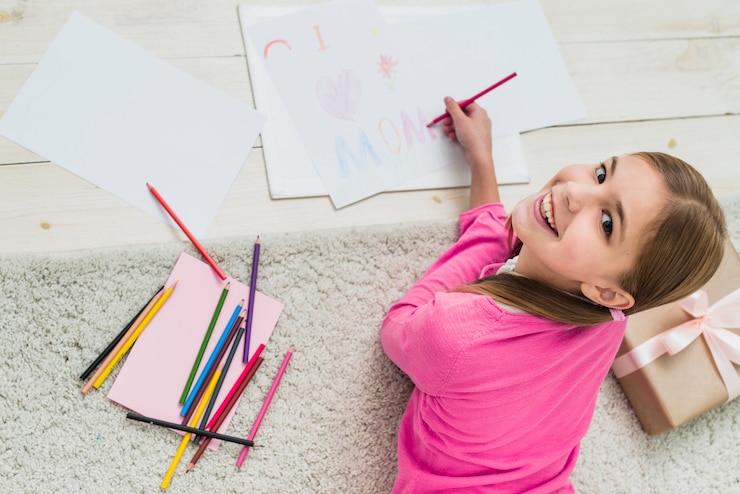 Free Photo happy girl drawing i love mom on paper 