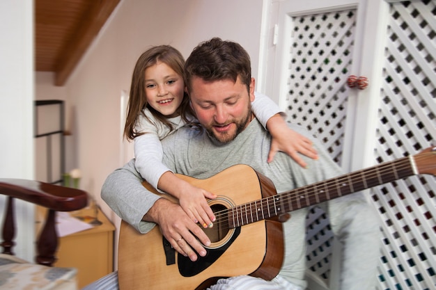 happy girl embracing her father while holding a guitar